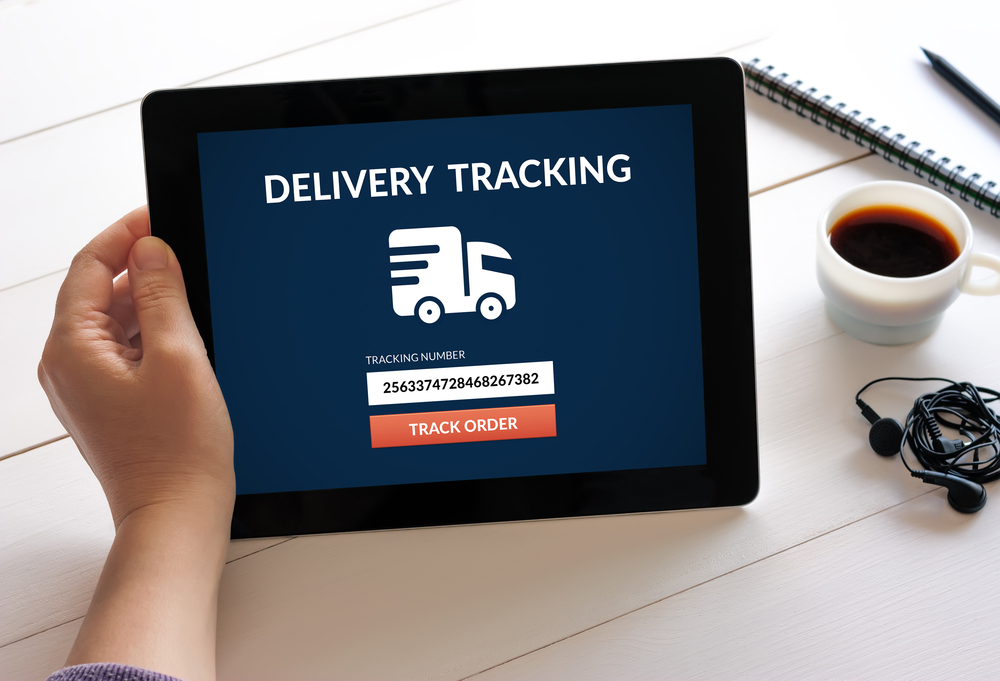 Hand holding digital tablet computer with delivery tracking concept on screen.