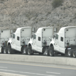 Blog Title Image of 4 white semi trucks no loads, on side of the highway.