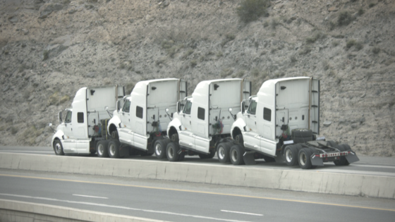 Blog Title Image of 4 white semi trucks no loads, on side of the highway.