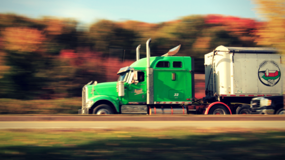Neon Green Semi-Truck speeds past fall foliage on the highway